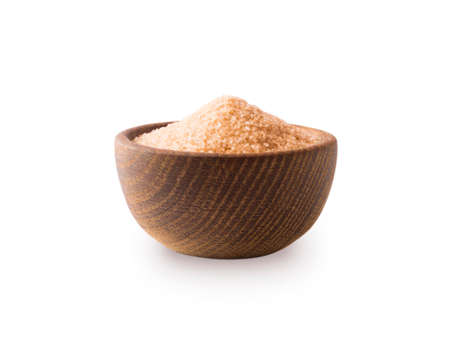 Heap of cane sugar isolated on white background. Heap of brown sugar on white background. Wooden bowl of dark sugar isolated on white background. Sugar in wooden bowl for cooking, isolated. Selective focus.の写真素材