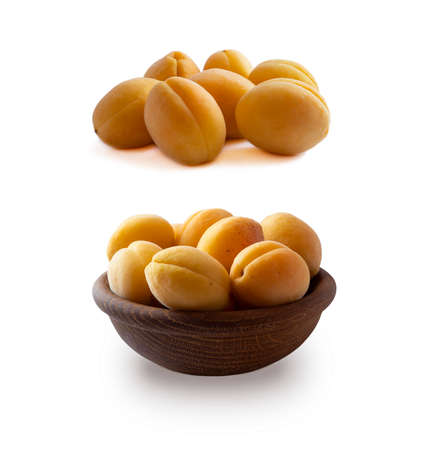 Heap of apricots isolated on white background. Ripe apricots with copy space for text. Apricots in a wooden bowl on white background. Fresh summer fruits. Set of apricots.の写真素材