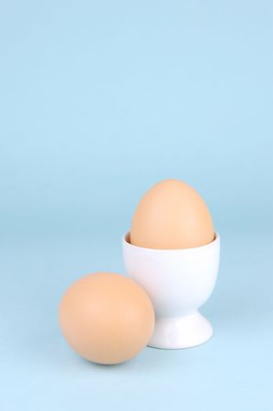 Hard boiled eggs and egg cups isolated against a blue background