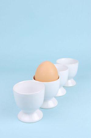 Hard boiled eggs and egg cups isolated against a blue backgroundの写真素材