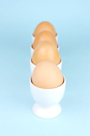 Hard boiled eggs and egg cups isolated against a blue backgroundの写真素材