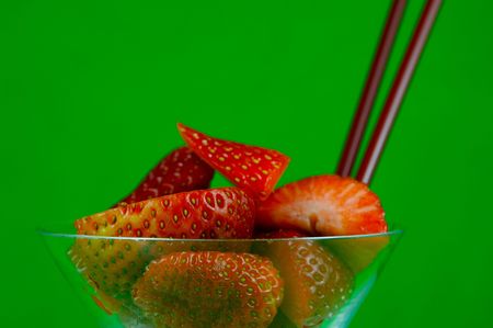 Strawberries in a cocktail glass islolated against a green backgroundの写真素材