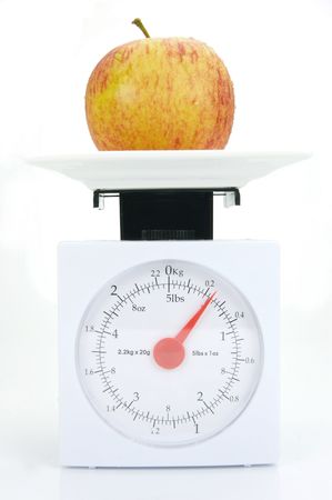 A red apple on top of a set of kitchen scales isolated against a white backgroundの写真素材