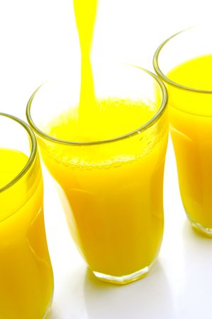 Orange juice being poured into a glass isolated against a white backgroundの写真素材