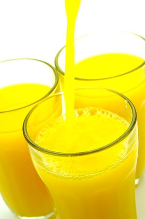 Orange juice being poured into a glass isolated against a white backgroundの写真素材