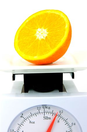 A sliced orange on top of a set of kitchen scales isolated against a white backgroundの写真素材