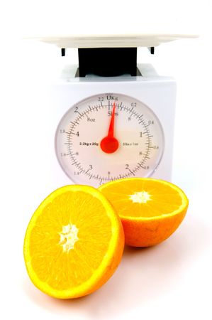 A sliced orange on top of a set of kitchen scales isolated against a white backgroundの写真素材