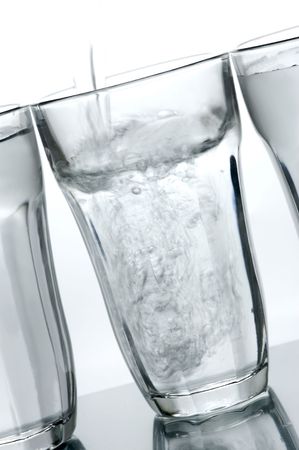 Glasses of drinking water backlit against a white background