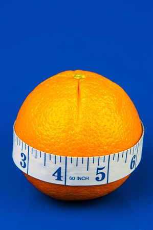 Conceptual health and diet image of an orange and a measuring tape isolated against a blue backgroundの写真素材