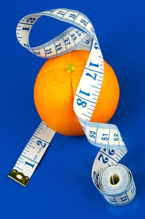 Conceptual health and diet image of an orange and a measuring tape isolated against a blue backgroundの写真素材