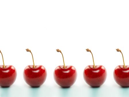 Fresh seasonal red cherries isolated against a powder blue backgroundの写真素材