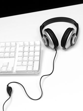 A desktop computer with a set of headphones isolaterd against a white backgroundの写真素材