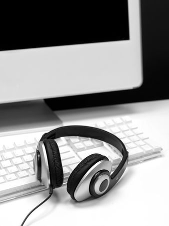 A desktop computer with a set of headphones isolaterd against a white background
