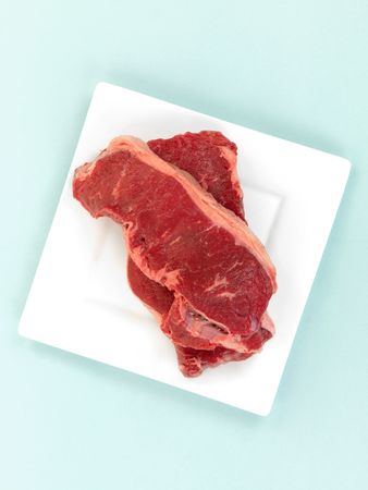Porterhouse steak on a plate isolated against a blue background