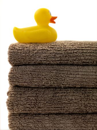 A stack of bath towels and a rubber duck isolated against a white backgroundの写真素材