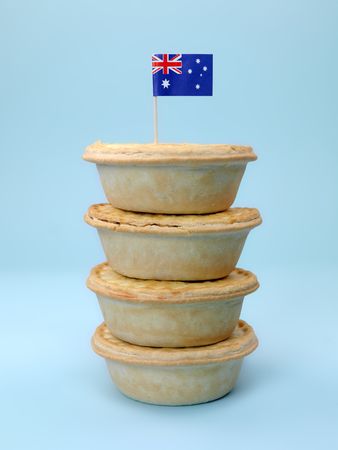 A stack of  Australian meat pies isolated against a blue background with an Australian flagの写真素材