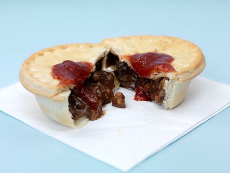 An Australian meat pie isolated against a blue backgroundの写真素材