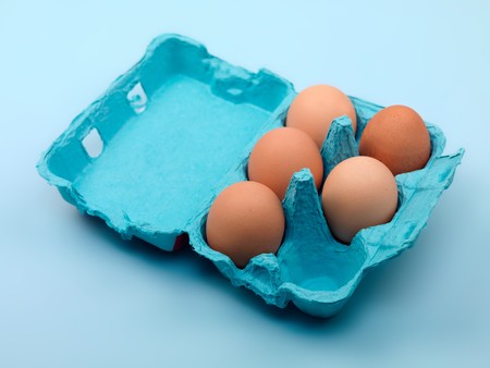 Eggs in a egg carton isolated against a blue backgroundの写真素材