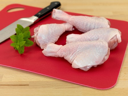 Raw chicken drumsticks on a kitchen benchの写真素材