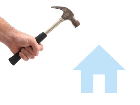 A metal hammer hammering a house isolated against a white backgroundの写真素材