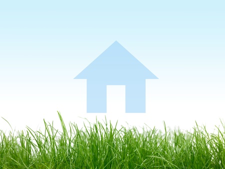 Green grass with a house isolated against a blue skyの写真素材