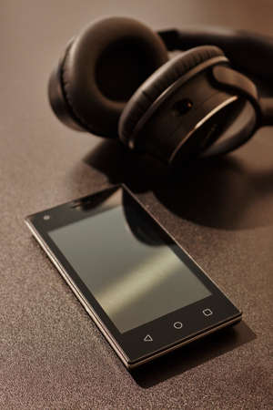 A studio photo of a mobile phone with headphonesの写真素材