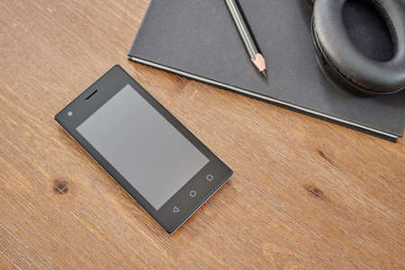 A studio photo of a mobile phone with headphonesの写真素材