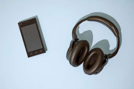 A studio photo of a mobile phone with headphonesの写真素材