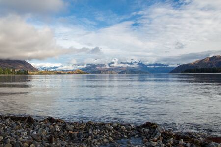 Snow covered mountains in front of beautiful lake in wanaka new zealand south islandの写真素材