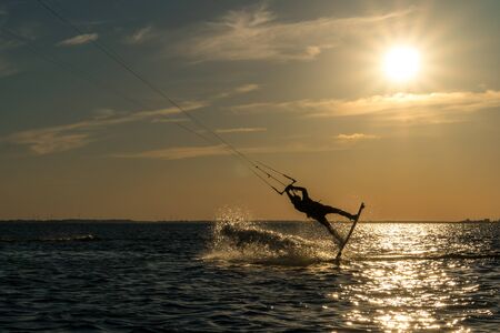 kitesurfer doing unhooked backroll in sunset with sunstar and beautiful silhouetteの写真素材