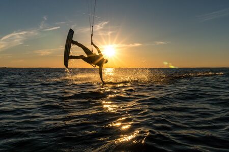 kitesurfer doing handslide in sunset with sunstar and beautiful silhouetteの写真素材