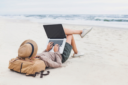 Young woman using laptop computer on a beach. Freelance work conceptの写真素材