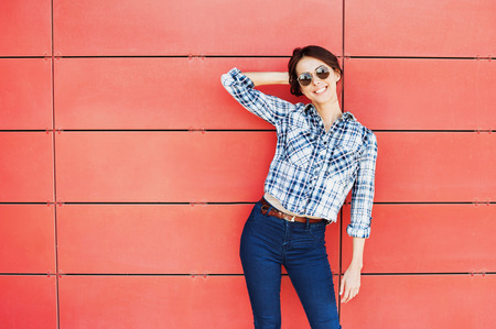 Beautiful trendy model posing against red wallの写真素材