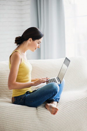 Young beautiful woman using a laptop computer at homeの写真素材