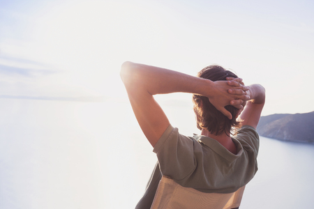 Enjoying life. Back side of young man looking at the sea, vacations lifestyle conceptの写真素材