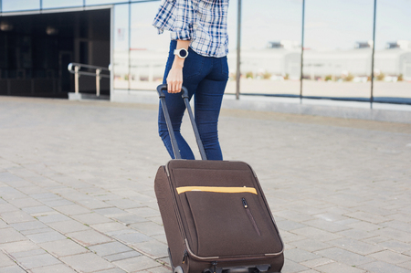 Closeup of young woman walking with luggage suitcase. Vacations, travel and active lifestyle conceptの写真素材