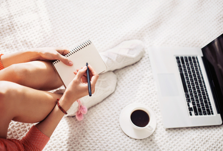Young woman writing in notebook at homeの写真素材