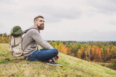 Young man traveler sitting on top of the hill, travel and active lifestyle conceptの写真素材