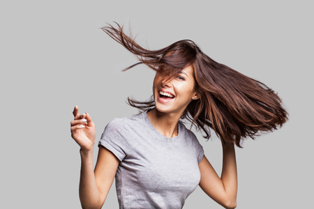 Beautiful girl with long hair laughing, dancing and enjoying lifeの写真素材