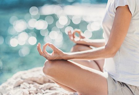 Young woman practicing yoga near the sea in summer. Harmony and meditation concept. Healthy lifestyle. Enjoying life and summerの写真素材