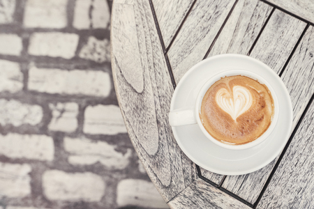 Cup of cappuccino coffee on a table in a coffee shop on a city streetの写真素材