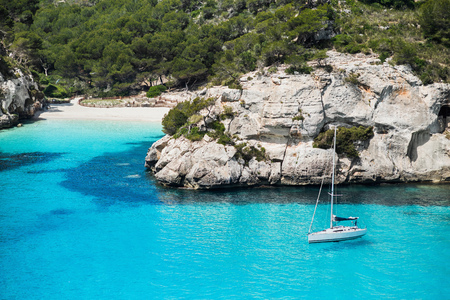 Beautiful bay in Mediterranean sea with sailing boat, Menorca island, Spain. Yachting, travel and active lifestyle conceptの写真素材