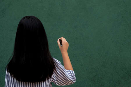 back side of thoughtful child girl on white background. Hold pen writing on blank  space text.の写真素材