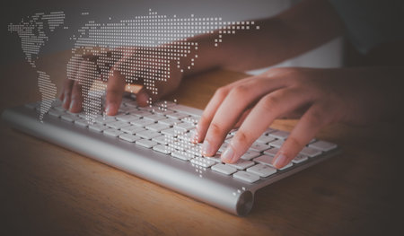Close-up of female hands typing on the laptop keyboard with perspective world map technology....