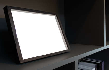 Side view or perspective of wooden picture frame with copies space or blank white screen on shelfの写真素材