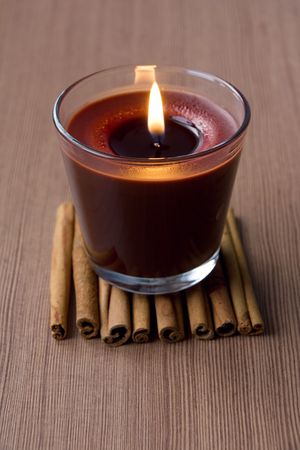 Candle in the glass and cinnamon sticksの写真素材