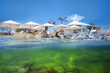 Exotic beach, half under water on the background of the uncovered sun umbrellasの写真素材
