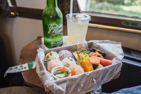 Yufuin, Oita, Kyushu, Japan - October 14, 2018 : Yufuin cider, special drink in Yufuin No Mori train, limited express train, route between Hakata station to Yufuin station, green bottle and bento sushiのeditorial素材