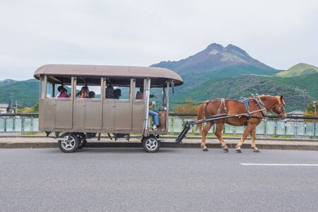 Yufuin, Oita, Kyushu, Japan - October 14, 2018 : The tourist on the horse carriage ride around Yufuin, river and Yufu mountain backgroundのeditorial素材