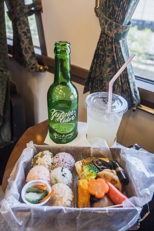 Yufuin,Oita,Kyushu,Japan - October 14, 2018 :Yufuin cider, special drink in Yufuin No Mori train, limited express train, route between Hakata station to Yufuin station, green bottle and bento sushiのeditorial素材